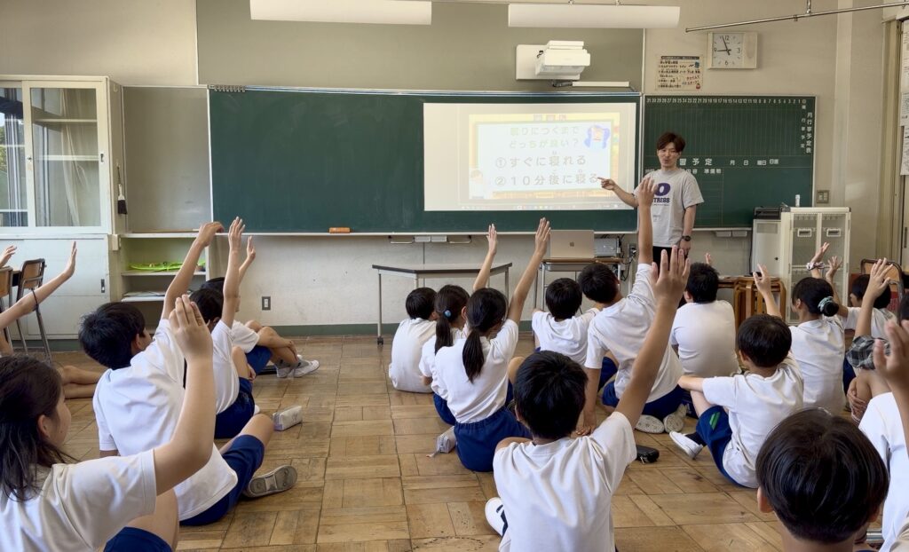 クイズに参加して手を挙げる小学生